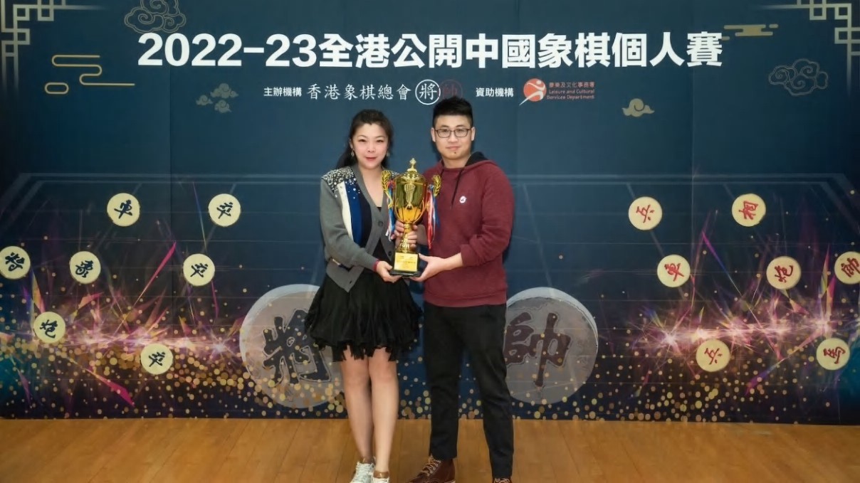 香港象棋總會秘書長黃嘉寶（左）為新冠軍鄭彥隆（右）頒發獎項